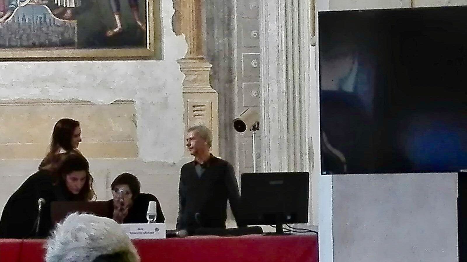 Un'immagine che ritrae dispositivo elettronico, dispositivo di visualizzazione, sala, udito e pubblico.