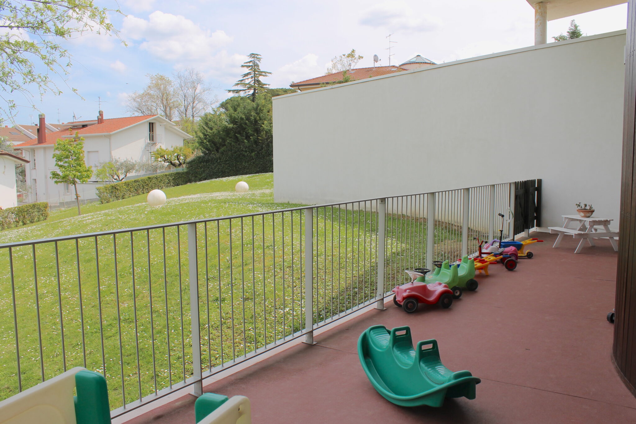 Un'immagine che ritrae ombra, balcone, prato, recinzione e cortile.