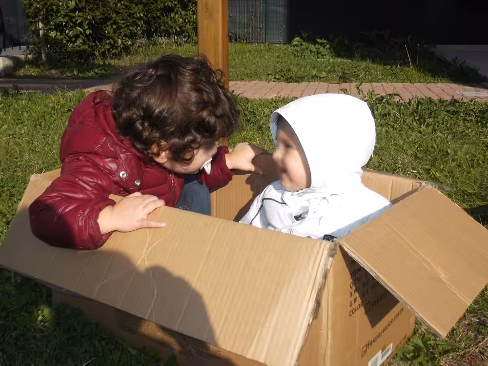 Un'immagine che ritrae cartone, scatola di spedizione, prodotto di carta, bambino e imballaggio in cartone.