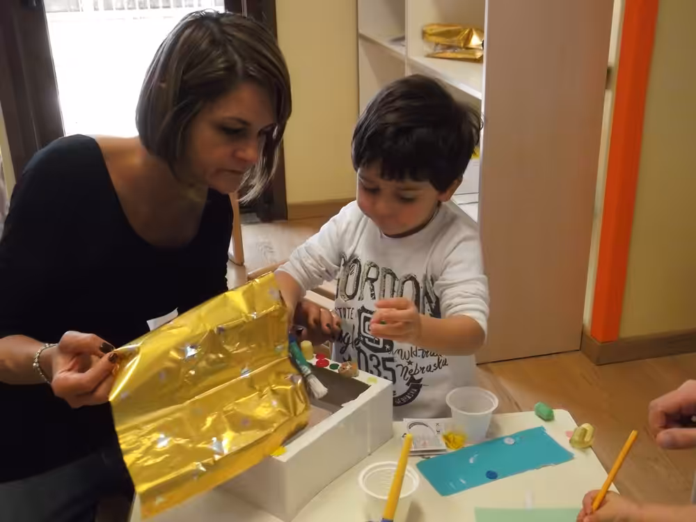 Un'immagine che ritrae braccio, mano, dito, bambino e tavolo.