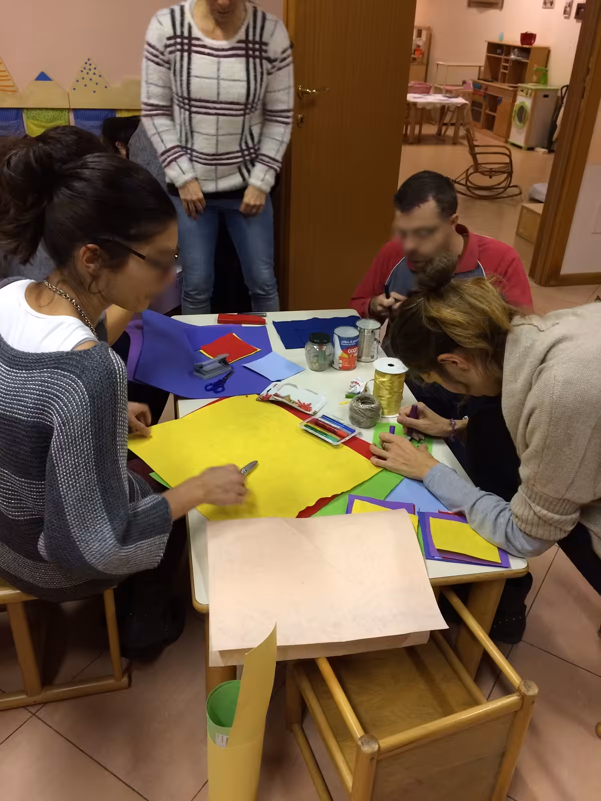 Un'immagine che ritrae braccio, mobilia, mano, tavolo e carta.