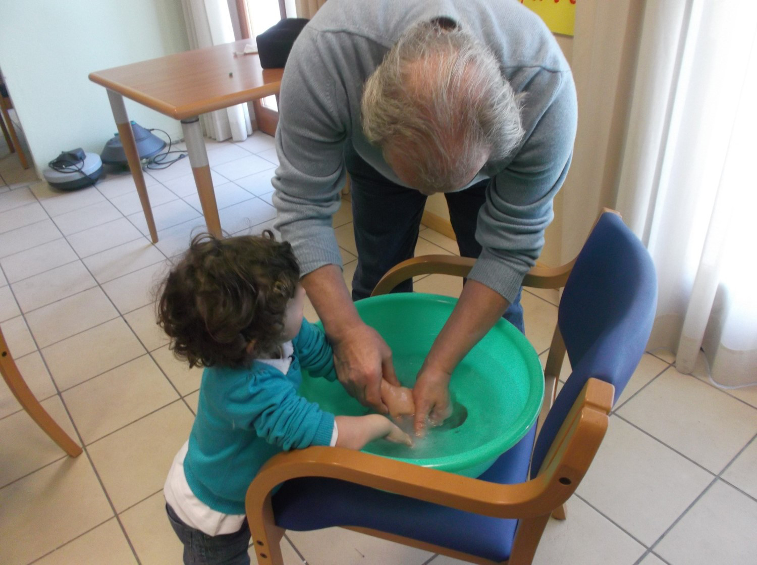 Un'immagine che ritrae mobilia, sedia, bambino, seduta e bambino che fa i primi passi.